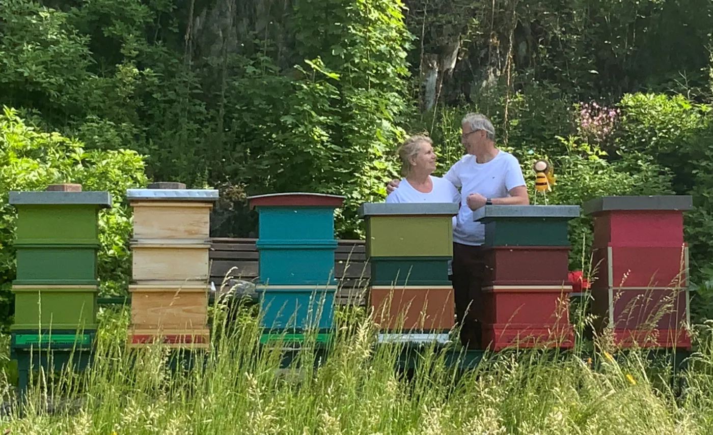 Michaela Buchinger und Karl Brenner bei ihren bunten Bienenstöcken am Waldrand